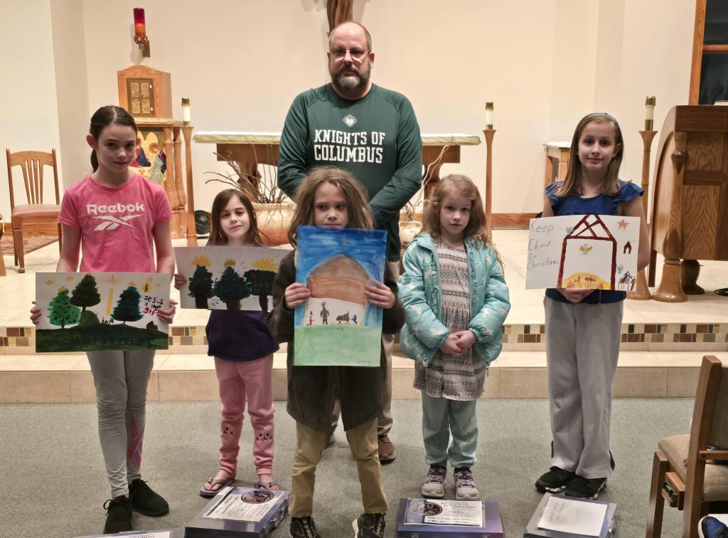 Children displaying their Christmas poster artwork during a Knights of Columbus award presentation